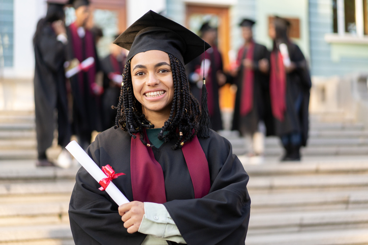 A university student clasping her certificate of graduation