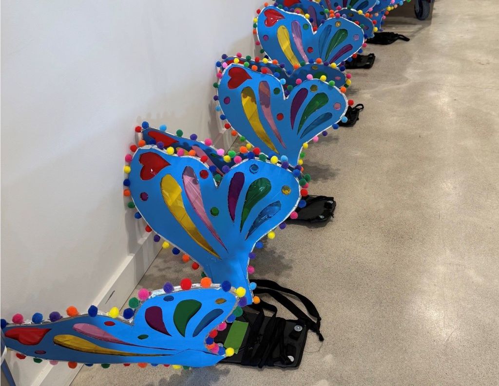Colorful handmade butterfly decorations with pom-poms and patterns on a white background.