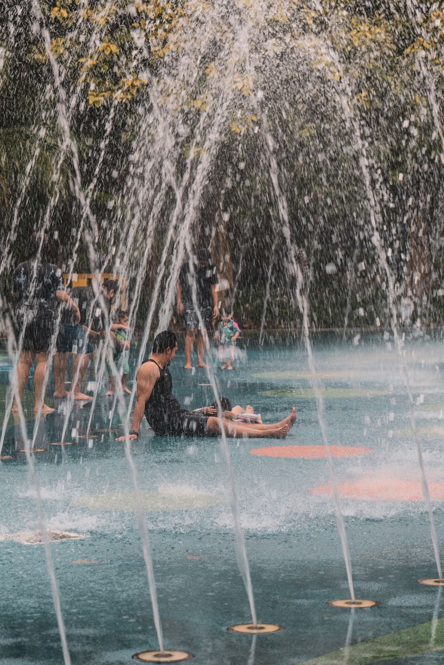 a man sitting in the middle of a fountain in a city
