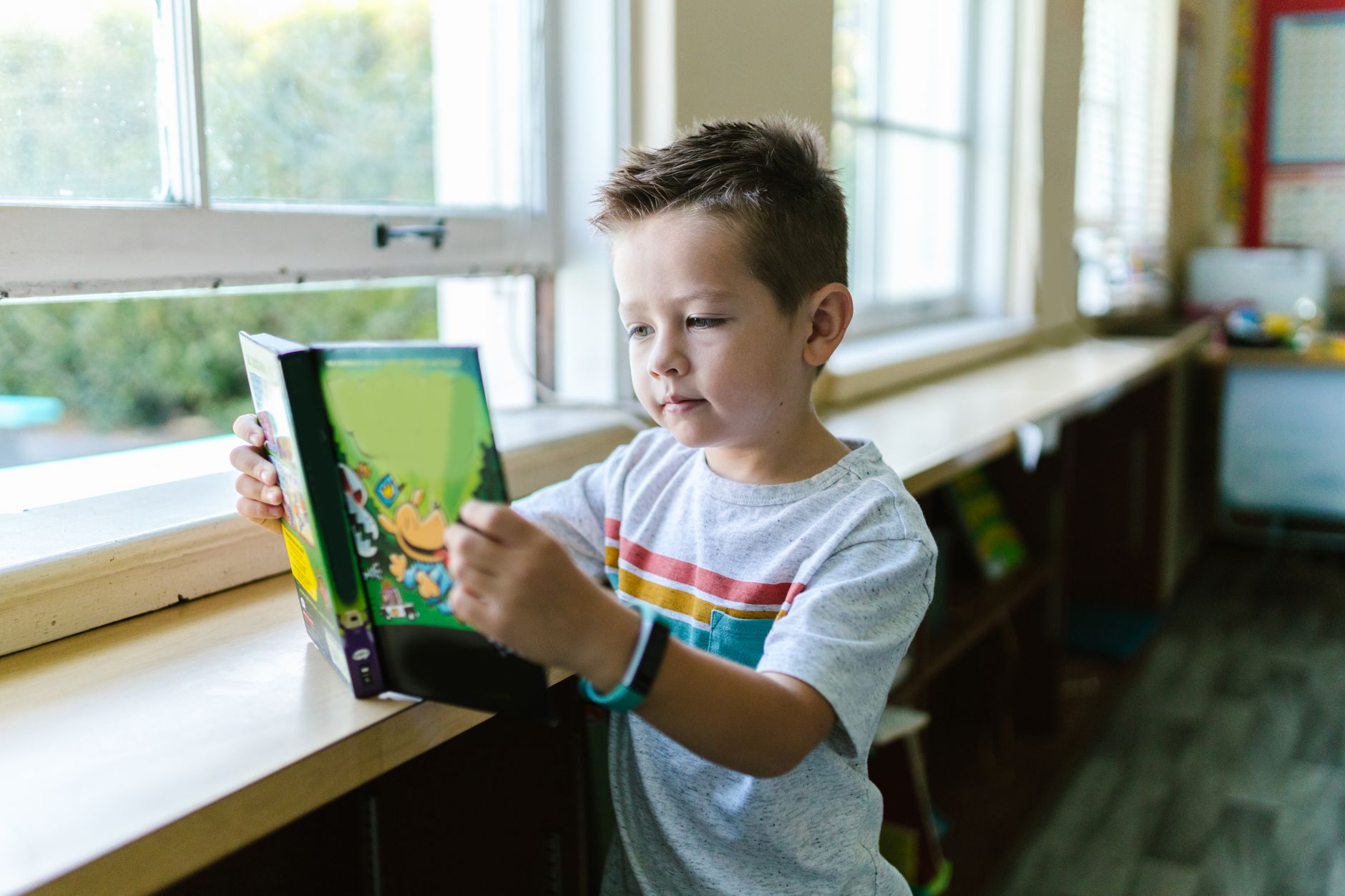 boy in gray crew neck t shirt holding a book