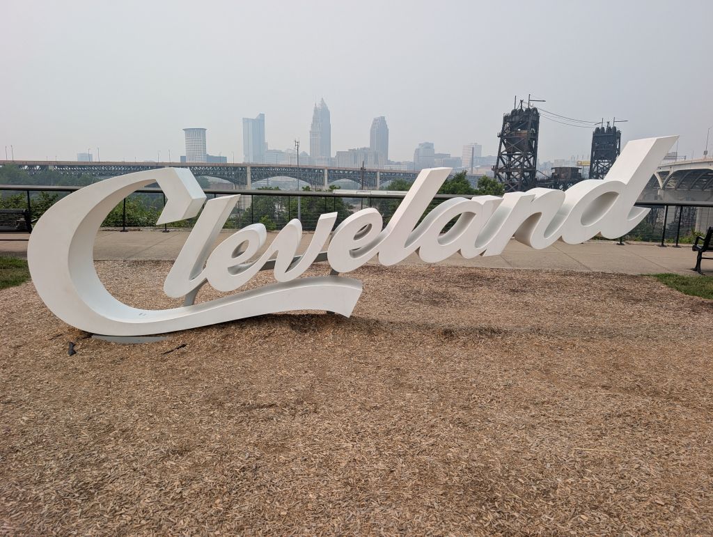 Large white "Cleveland" sign in a park with a cityscape in the background.