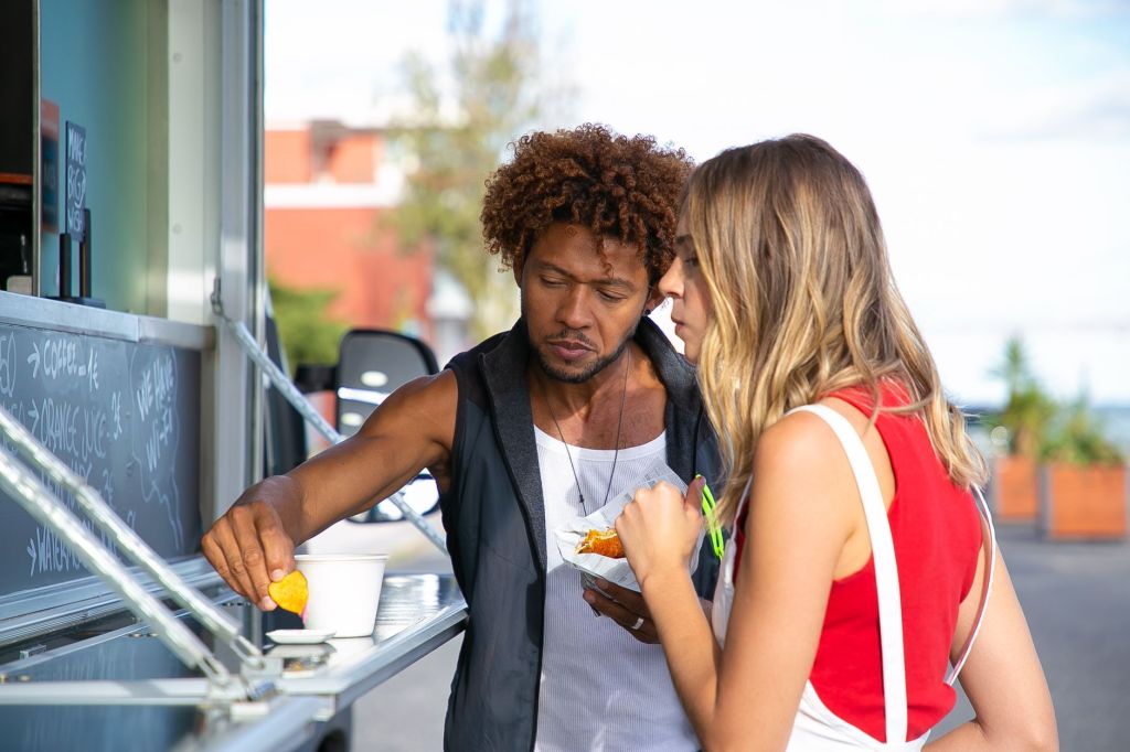 multiethnic young diverse couple eating fast food in truck cafe
