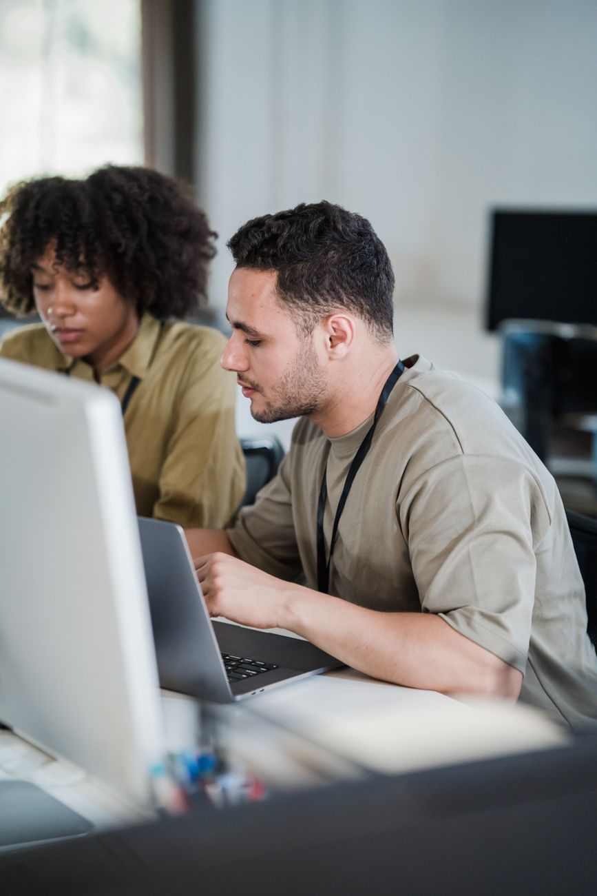 vertical shot of man and woman using computers at desk