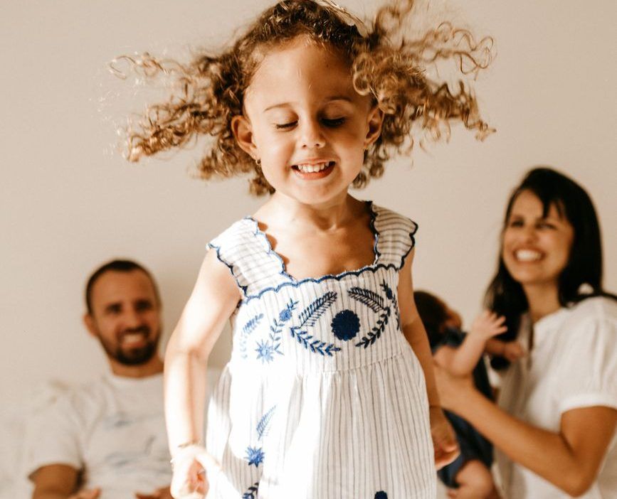 happy little kid having fun on bed with cheerful parents